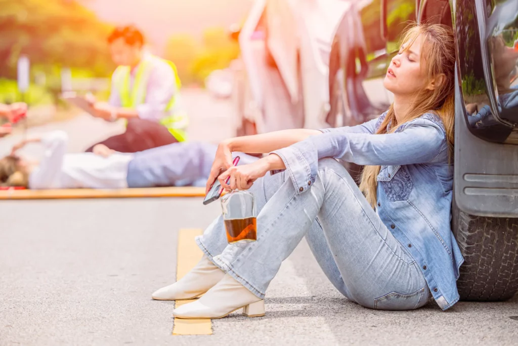 a person sitting on the ground with a drink in her hand