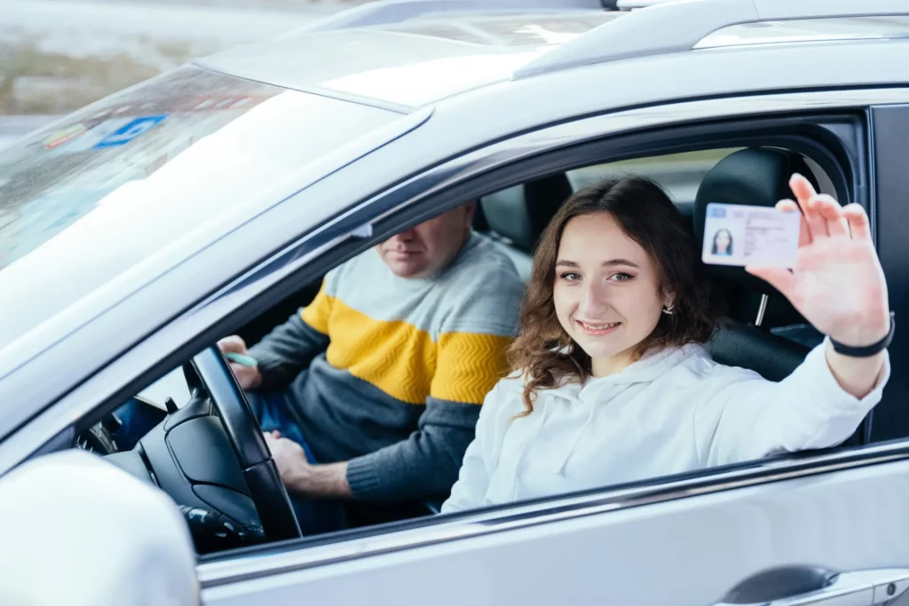 a person sitting in a car holding a driver's license